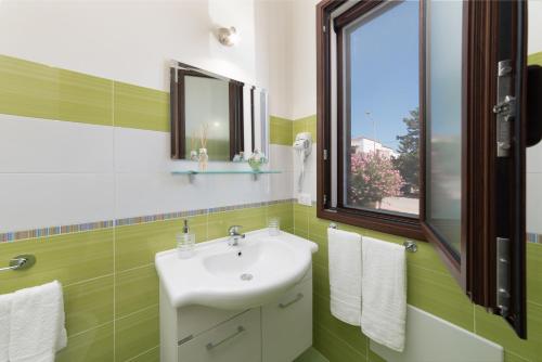 uma casa de banho verde e branca com um lavatório e uma janela em Tra la montagna e il mare em San Vito lo Capo