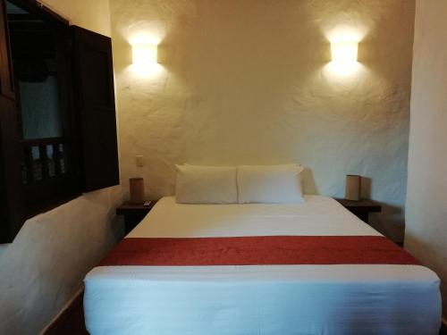 a bed in a room with two lights on the wall at Casona CHARA in Barichara
