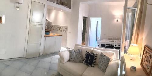 uma sala de estar com um sofá branco e uma cozinha em delizioso appartamento con terrazzetta em Porto Ercole