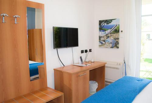 um quarto com uma cama e uma cómoda com uma televisão em Albergo Blueline em Tellaro