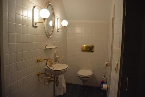 a bathroom with a sink and a toilet and lights at Gutshaus Wilhelmsruh in Möhnesee