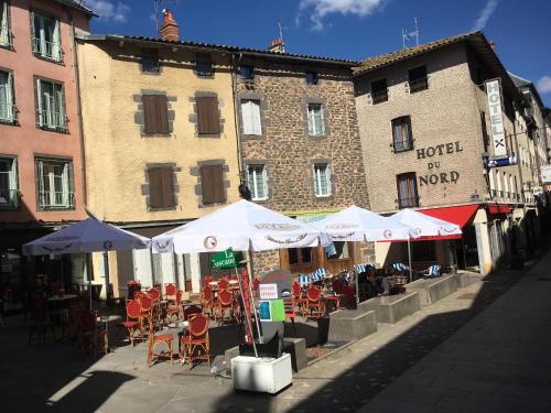 um café exterior com mesas, cadeiras e guarda-sóis em Hotel du Nord - Ville-Haute em Saint-Flour