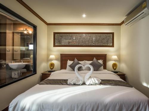 two white swans sitting on a bed in a bedroom at Lanna Tree Boutique Hotel in Chiang Mai