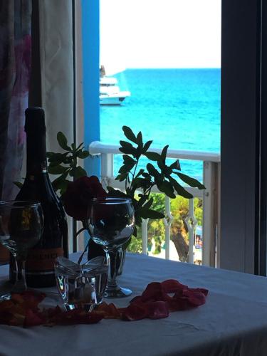a table with wine glasses and a view of the ocean at Stegna Sea & Sun in Archangelos