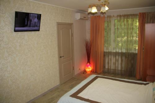 Un dormitorio con una cama y un televisor en la pared. en Современная 1-комнатная квартира, en Járkov