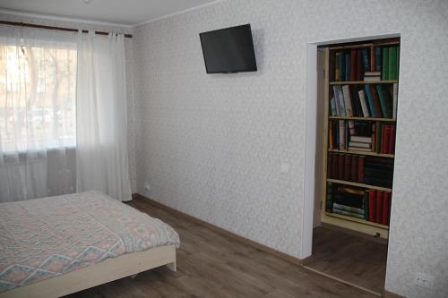 1 dormitorio con 1 cama y estantería con libros en Современная 1-комнатная квартира en Járkov