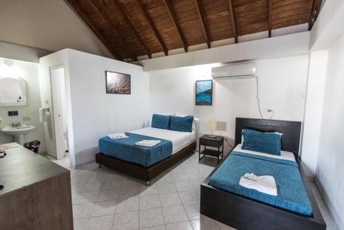 a bedroom with two beds and a bathroom with a sink at Sunset Hotel in San Andrés