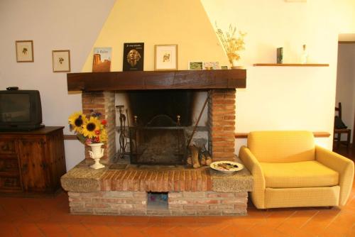 a living room with a brick fireplace and a yellow chair at Il Casolare in Penna