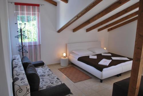 a bedroom with a bed and a couch and a window at Villa Lunaris in Maslinica