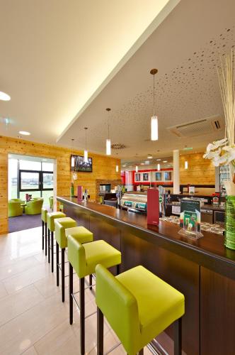 eine Bar mit gelben und grünen Hockern in einem Restaurant in der Unterkunft MT Hotel in Zeltweg