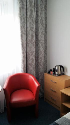 a red chair sitting in a room with a dresser at Hotel As in Biała Podlaska