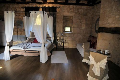 une chambre avec un lit à baldaquin avec des rideaux blancs dans l'établissement Chambres d'hôtes la Licorne, à Valojoulx