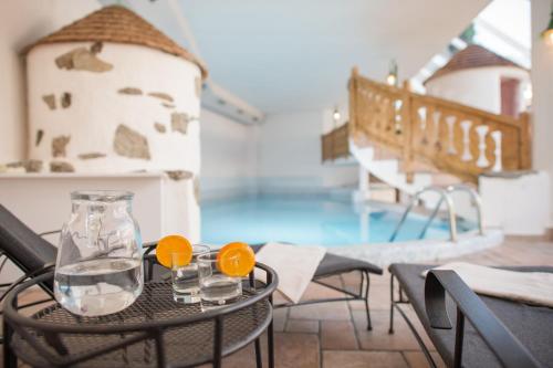 a table with glasses of water and a swimming pool at Hotel Mühlenerhof in Campo Tures