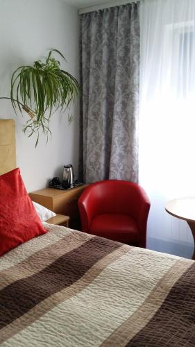 a bedroom with a bed and a red chair at Hotel As in Biała Podlaska