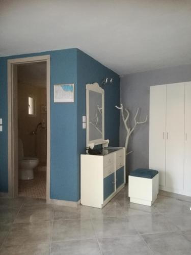 a bathroom with a blue wall with a sink and a mirror at Castle By The Sea in Artemida