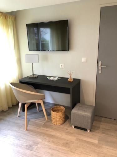 een bureau met een stoel en een televisie aan de muur bij La Bonne Auberge in Ségny