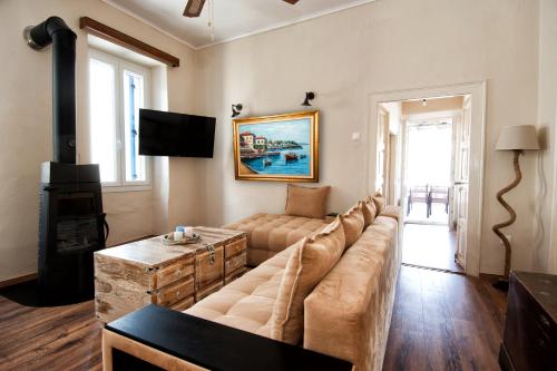 a living room with a large couch and a television at The Veranda of Gavrion-Exclusive, Centrally located with Seaview in Gavrion