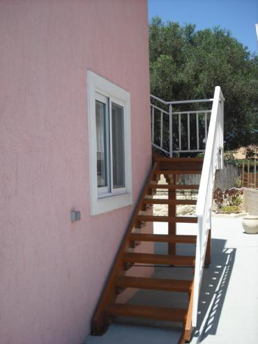a staircase leading up to a pink building with a window at ΣΑΡΑΝΤΗΣ ΜΑΡΚΌΠΟΥΛΟς in Lakithra