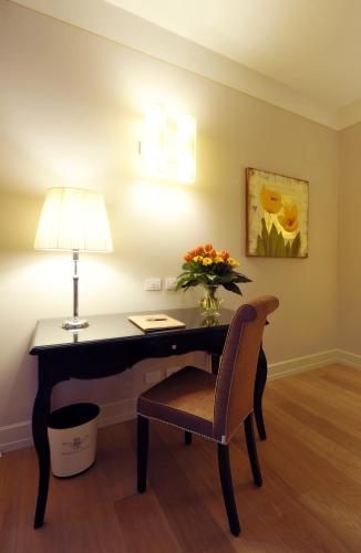 a desk with a lamp and a vase of flowers at Hotel Palazzo San Lorenzo & Spa in Colle Val D'Elsa