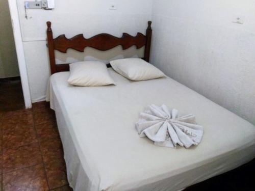 a white bed with a wooden headboard and white pillows at Hotel Cristal in Barra Bonita