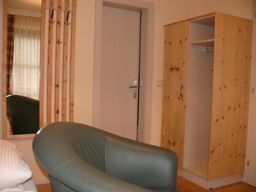 a green chair in a room with a closet at Gasthof-Pension zur Klause in Ratten