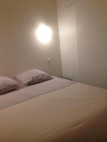 une chambre avec un lit avec une lumière sur le mur dans l'établissement Le Croix Roussien Lyon centre, à Lyon