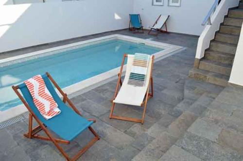 - deux chaises assises à côté de la piscine dans l'établissement Alojamento Charme, à Bombarral