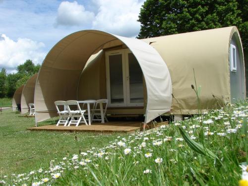 a tent with chairs and tables in a field of flowers at Camping Au Coeur de Vendome in Vendôme