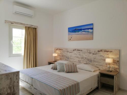 a white bedroom with a bed and a window at Evina Rooms & Suites in Kokkini Khanion