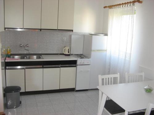 a kitchen with white cabinets and a table and a sink at Apartments&Rooms Milka in Starigrad-Paklenica