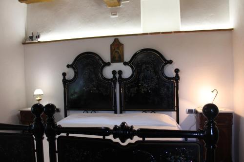 a bedroom with a black bed with white sheets at Camera Alabastro Fontesettimena in Volterra