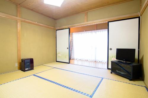 an empty living room with a television and a large window at Cyokiya Lake Saiko in Fujikawaguchiko