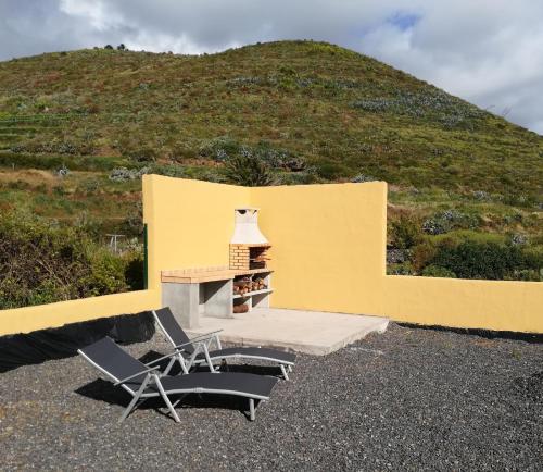 a yellow building with two chairs and a fireplace at Casa La Rehoya in Puntallana