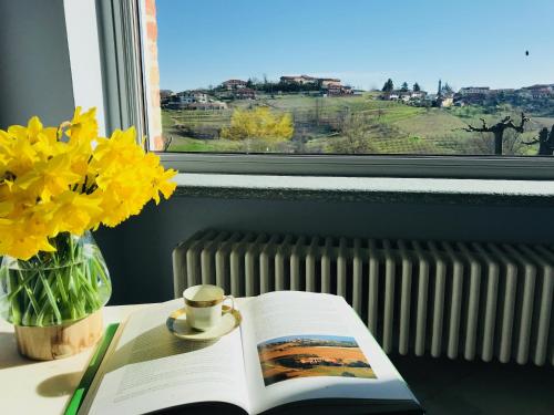 a book on a table with a cup of coffee and yellow flowers at La Granda agrirelax in San Martino Alfieri