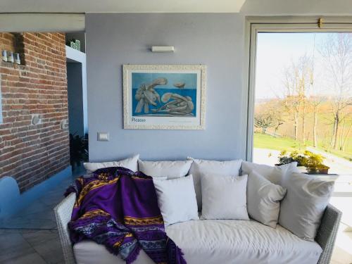 um sofá branco sentado num quarto com uma janela em La Granda agrirelax em San Martino Alfieri