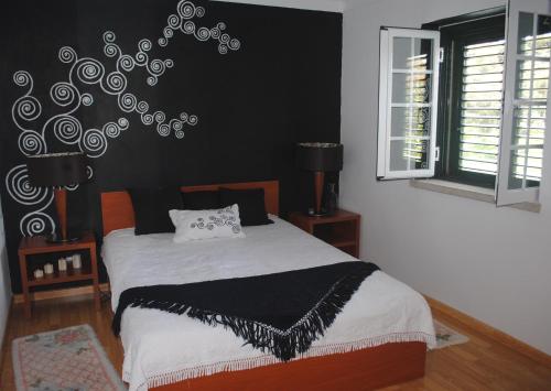 een slaapkamer met een bed met een zwarte muur bij Moradia Familia Escoto in Monsanto