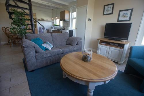 een woonkamer met een bank en een tafel bij Vakantiehuisje Smoek Holwerd, aan de Waddenzee in Holwerd