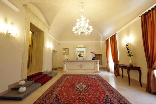 a living room with a chandelier and a red rug at Hotel Palazzo San Lorenzo & Spa in Colle Val D'Elsa