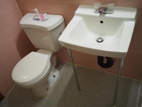 a bathroom with a white toilet and a sink at The Cavalier Inn in Winnipeg