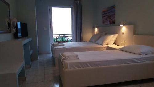 a hotel room with two beds and a television at Akrogiali Apartments in Agios Ioannis Kaspaka