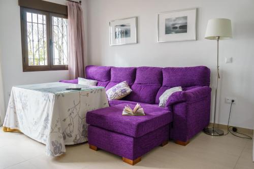 um sofá roxo e uma mesa numa sala de estar em "Ventana del Guadalquivir " em Baeza