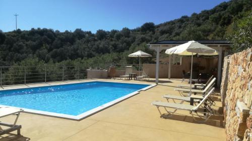 a swimming pool with chairs and umbrellas on a patio at Aksos Suites Accessible Accommodation in Ayiá