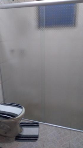 a bathroom with a toilet and a sliding shower door at hospedagem simples in Arapongas