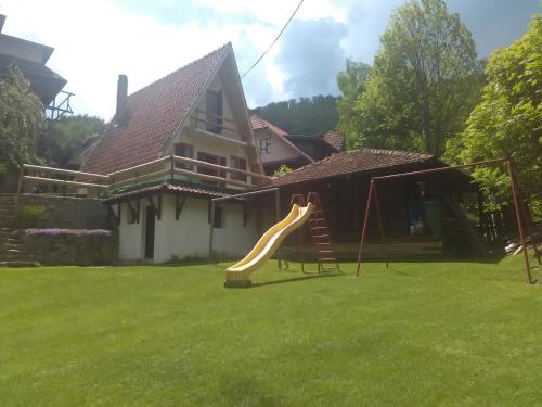 einen Hof mit Rutsche vor einem Haus in der Unterkunft Vikend kuca Bela Reka in Brzeće