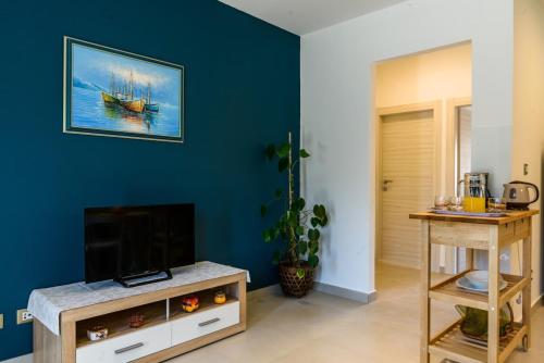 ein Wohnzimmer mit einem TV und einer blauen Wand in der Unterkunft Apartmani Marko i Ana in Marina