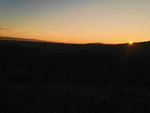 a sunset on a hill with the sun setting on the horizon at Casa Ollie in Castel San Gimignano