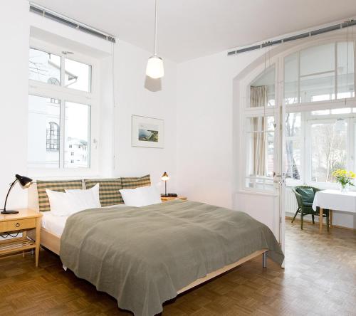 a white bedroom with a large bed and a desk at Dünenhaus Sellin in Ostseebad Sellin