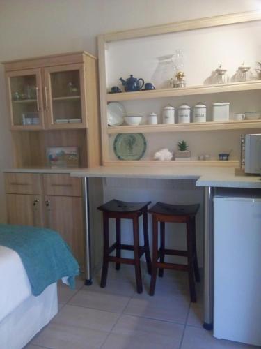 a kitchen with a counter and two stools in it at Kalahari Camelthorn Guesthouse and Camping in Askham