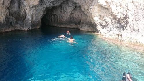 two people swimming in a cave in the water at Lithos Traditional Guest Houses in Xerokampos