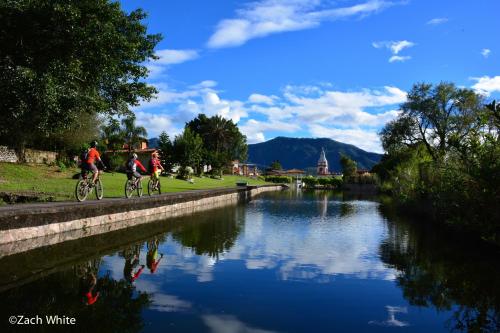 two people riding bikes on a path next to a river at Casa Tía Anita, Hotel Boutique in Mascota